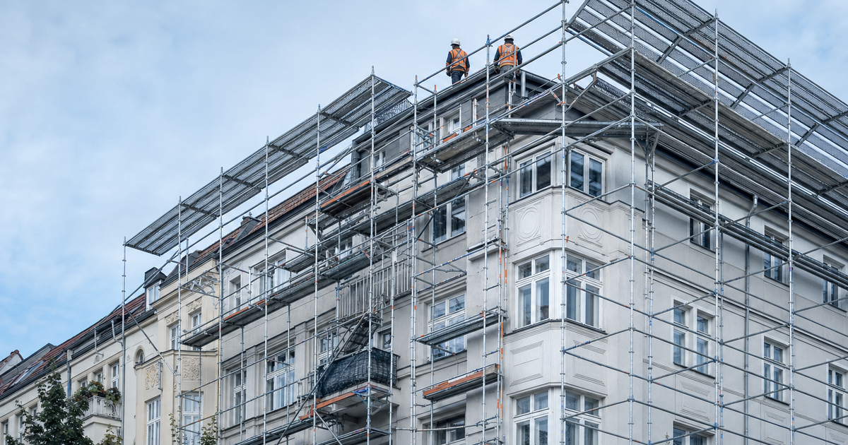Eingerüstete Baustelle mit Handwerkern verschiedener Gewerke am Fassadengerüst
